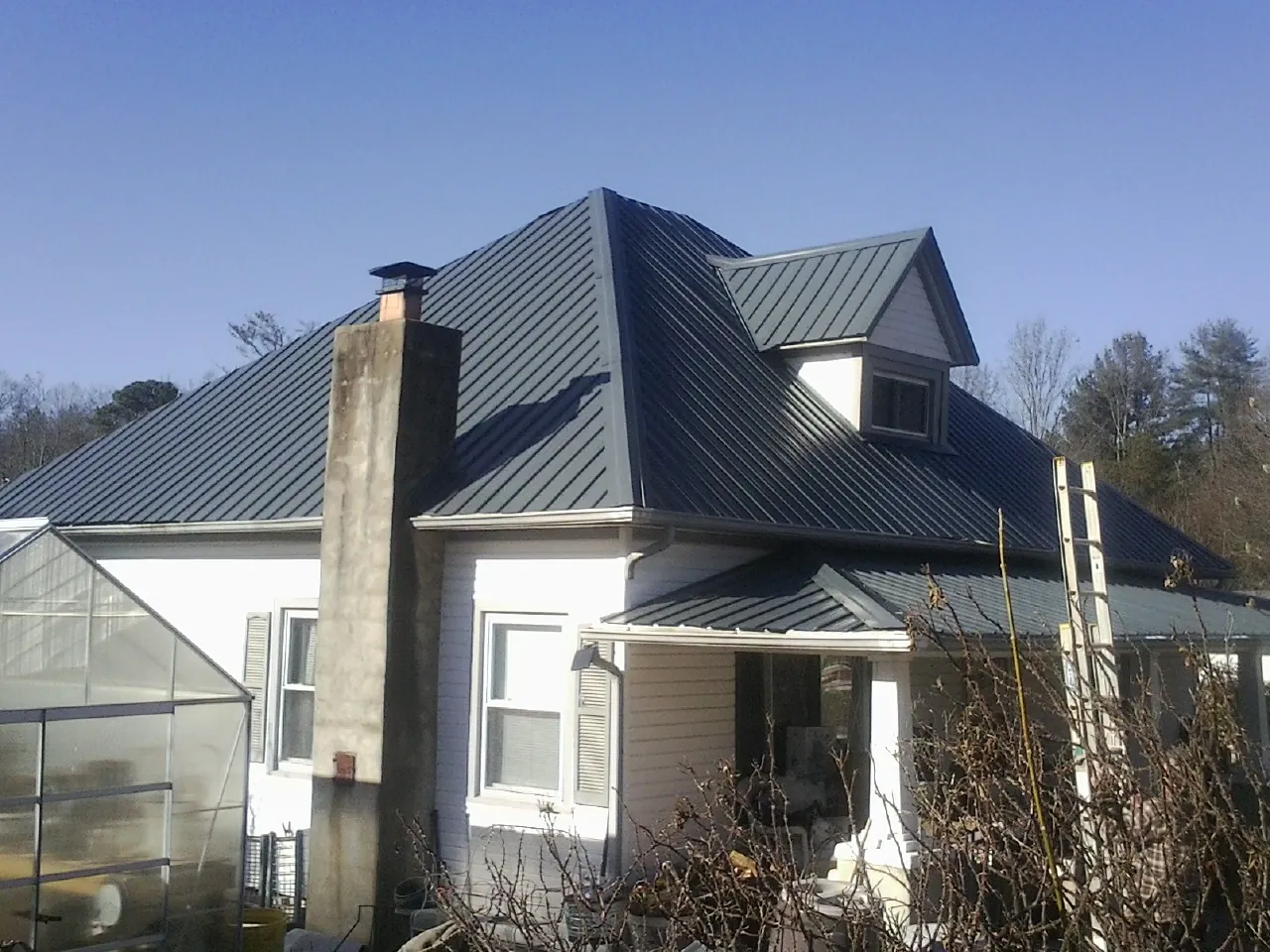 Dark blue standing seam metal roof on a white farmhouse with dormer — Slate & Tile Roof Repair by Roofing Brothers in Far Hills