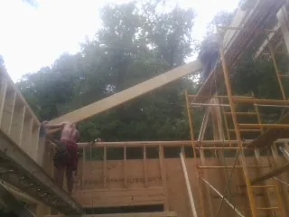 Carpenter raising a rafter beam on a new second story frame in Far Hills