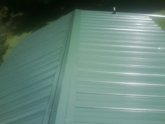 New green metal panels meeting at the ridge of a roof — Flat Roof Repair work by our crew in Far Hills
