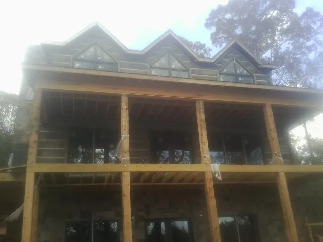 Dormers and porch framing on a large log home under construction — Roof Coating work by our crew in Far Hills