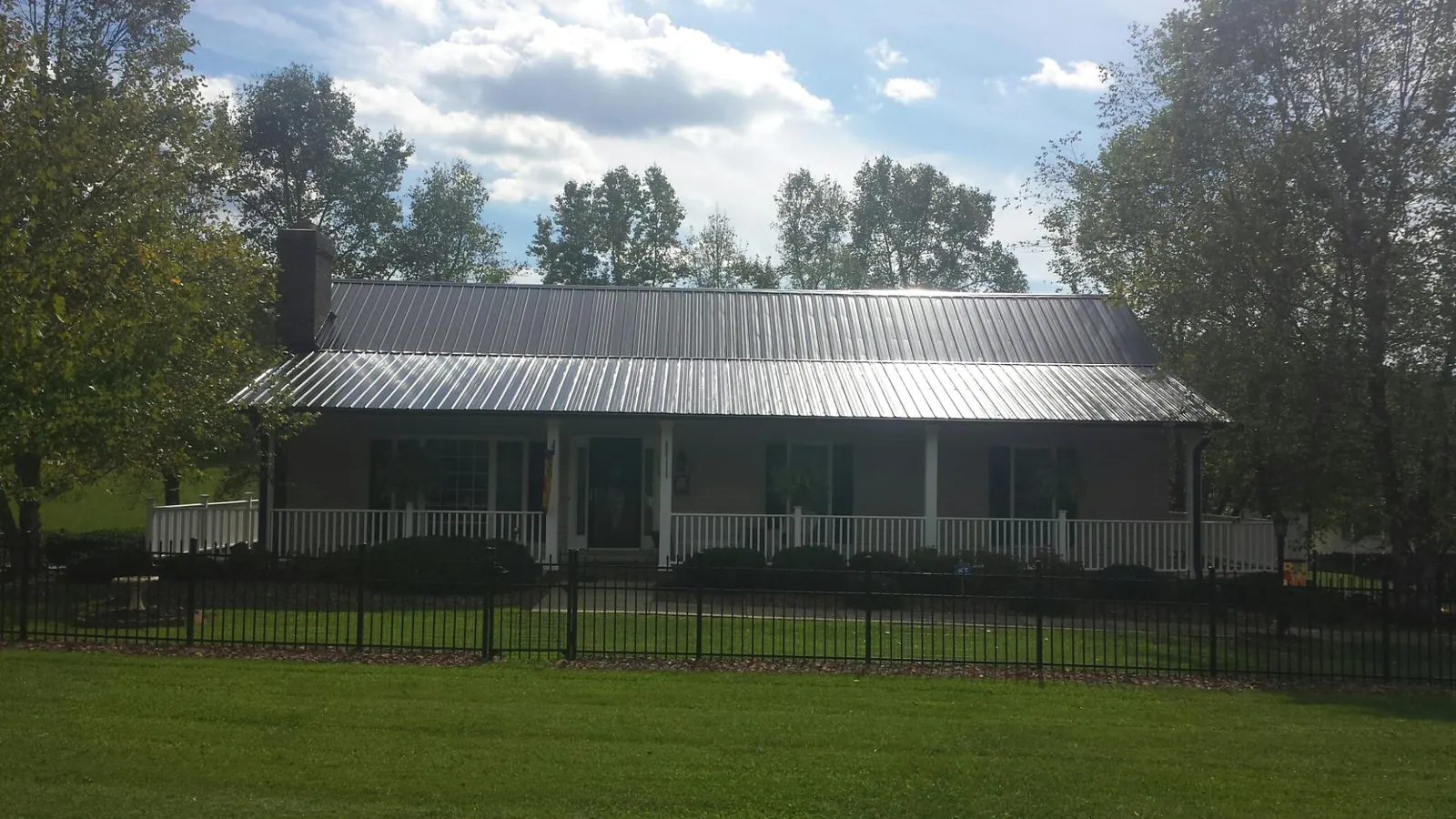 Gray metal roof on a brick ranch with a full width front porch — Gutter Guard Installation work by our crew in Far Hills