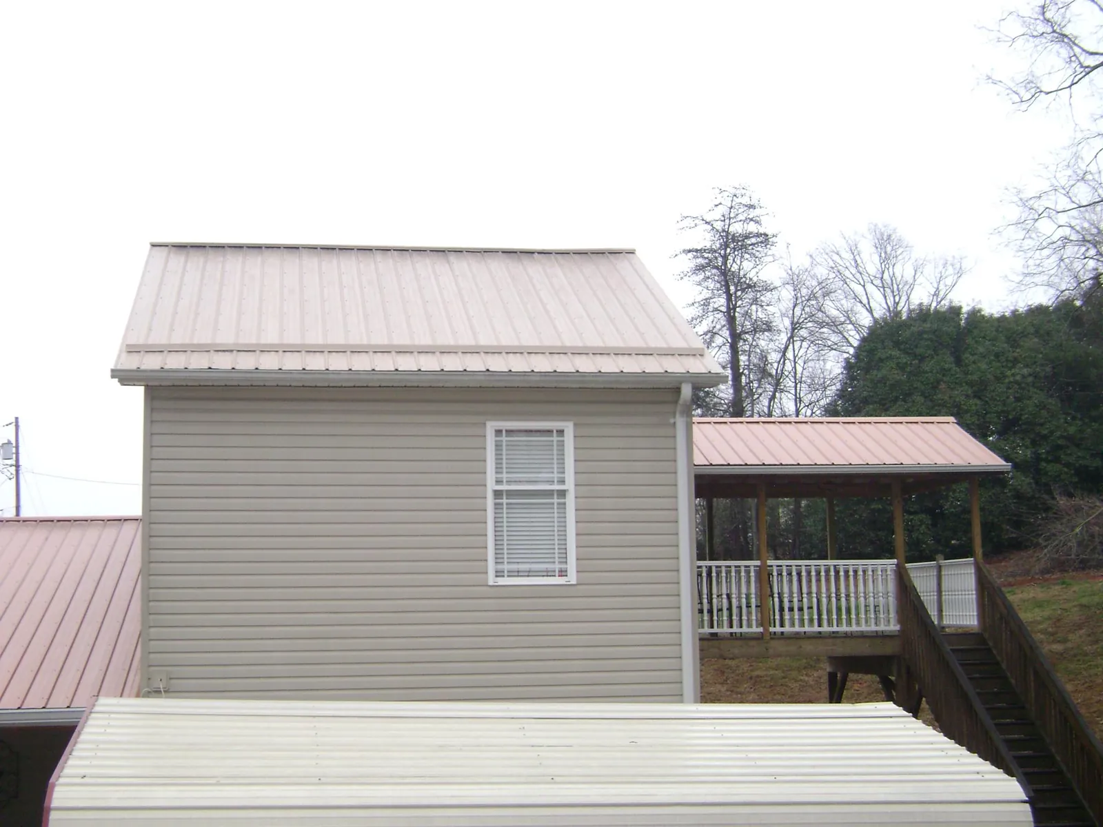 Tan metal roofs on a two story addition and attached porch, from a Roof Replacement job in Far Hills