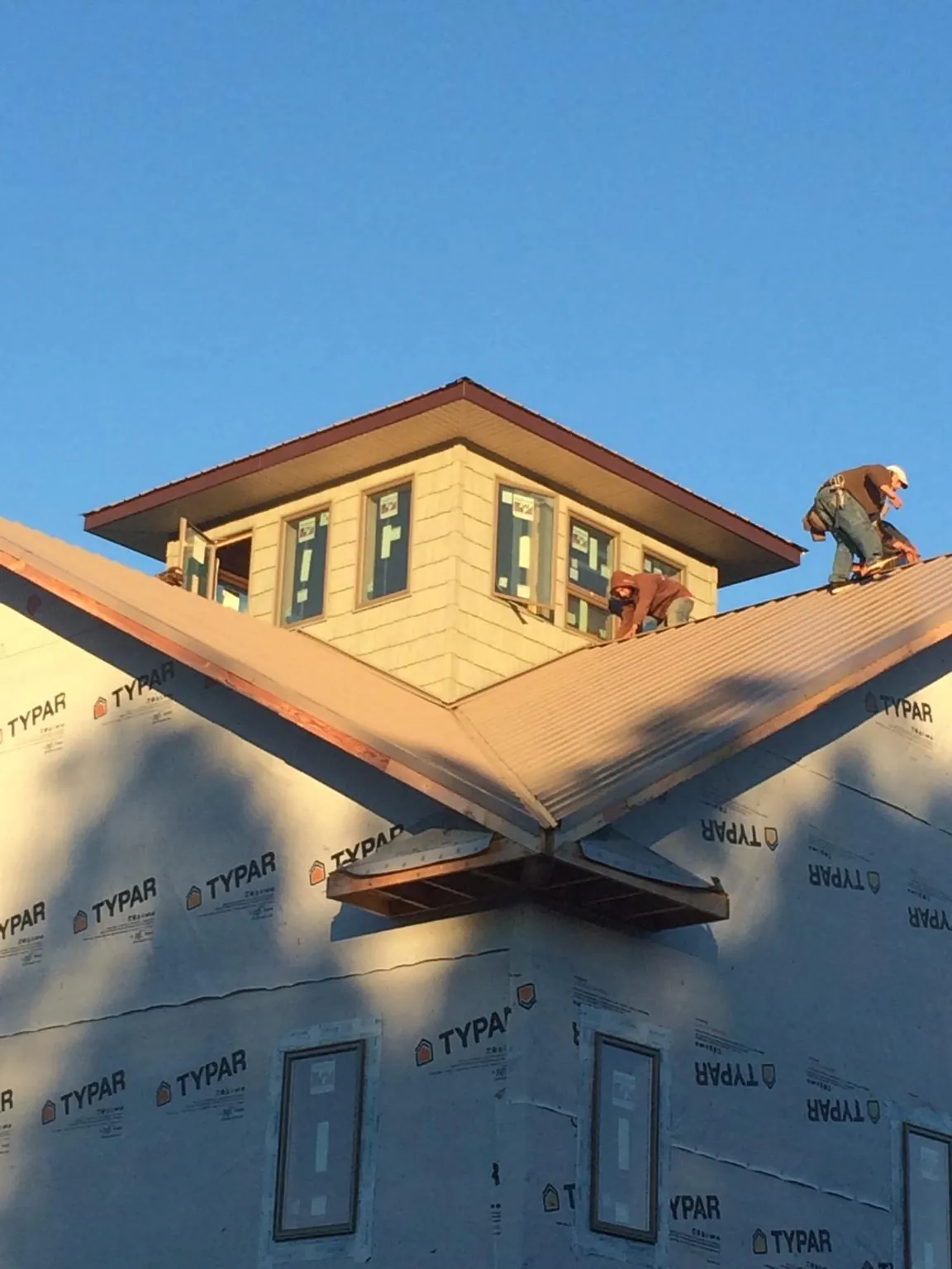Roofers working around a rooftop cupola on a new metal roof at sunset — Roof Waterproofing in Far Hills by Roofing Brothers